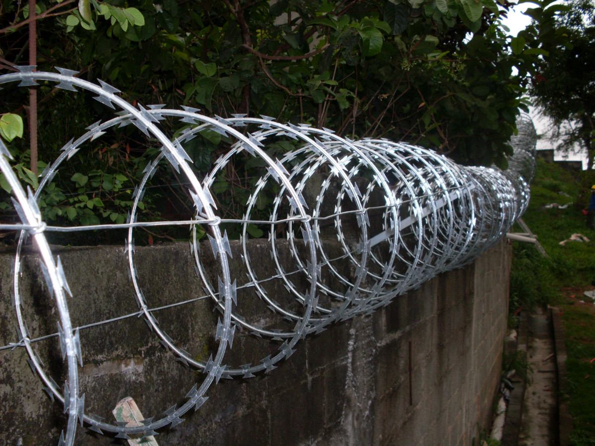 Arame concertina sobre um muro, reforcando a ideia de seguranca fisica do ambiente
